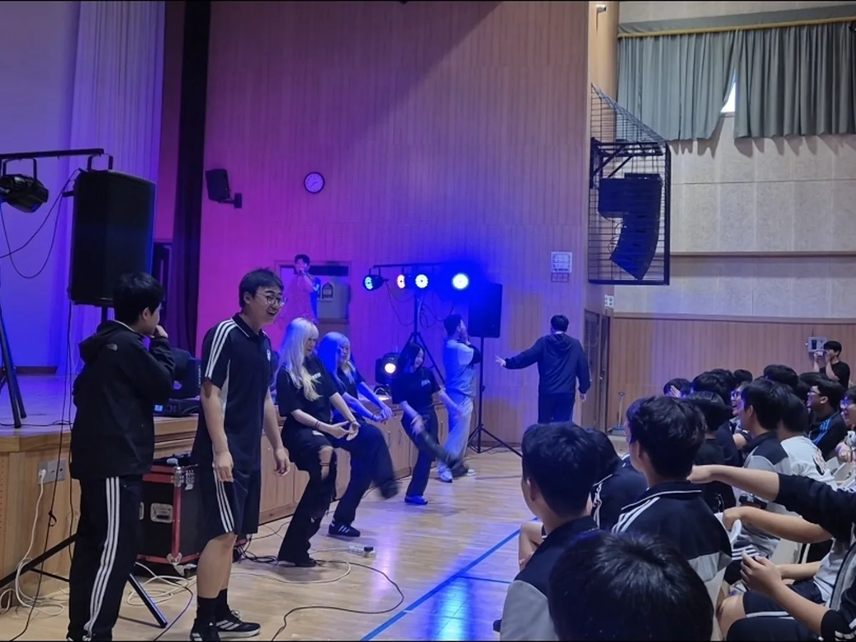 학교 체육관에서 공연자와 함께 동작을 따라 하며 참여하는 학생들